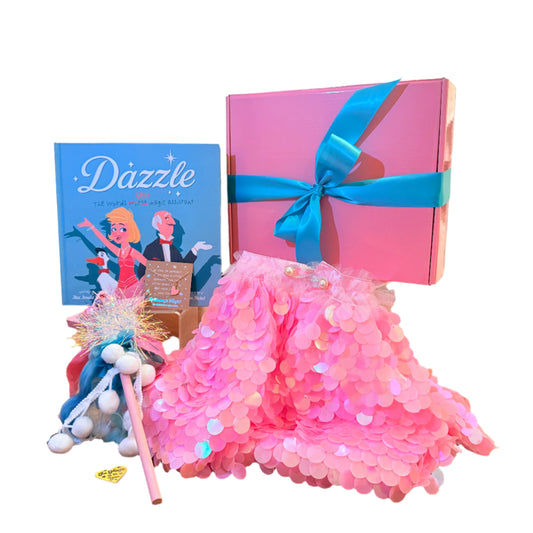 Pink sequin skirt with a blue ribbon, 'Dazzle' book, and decorative wand on a wooden table.